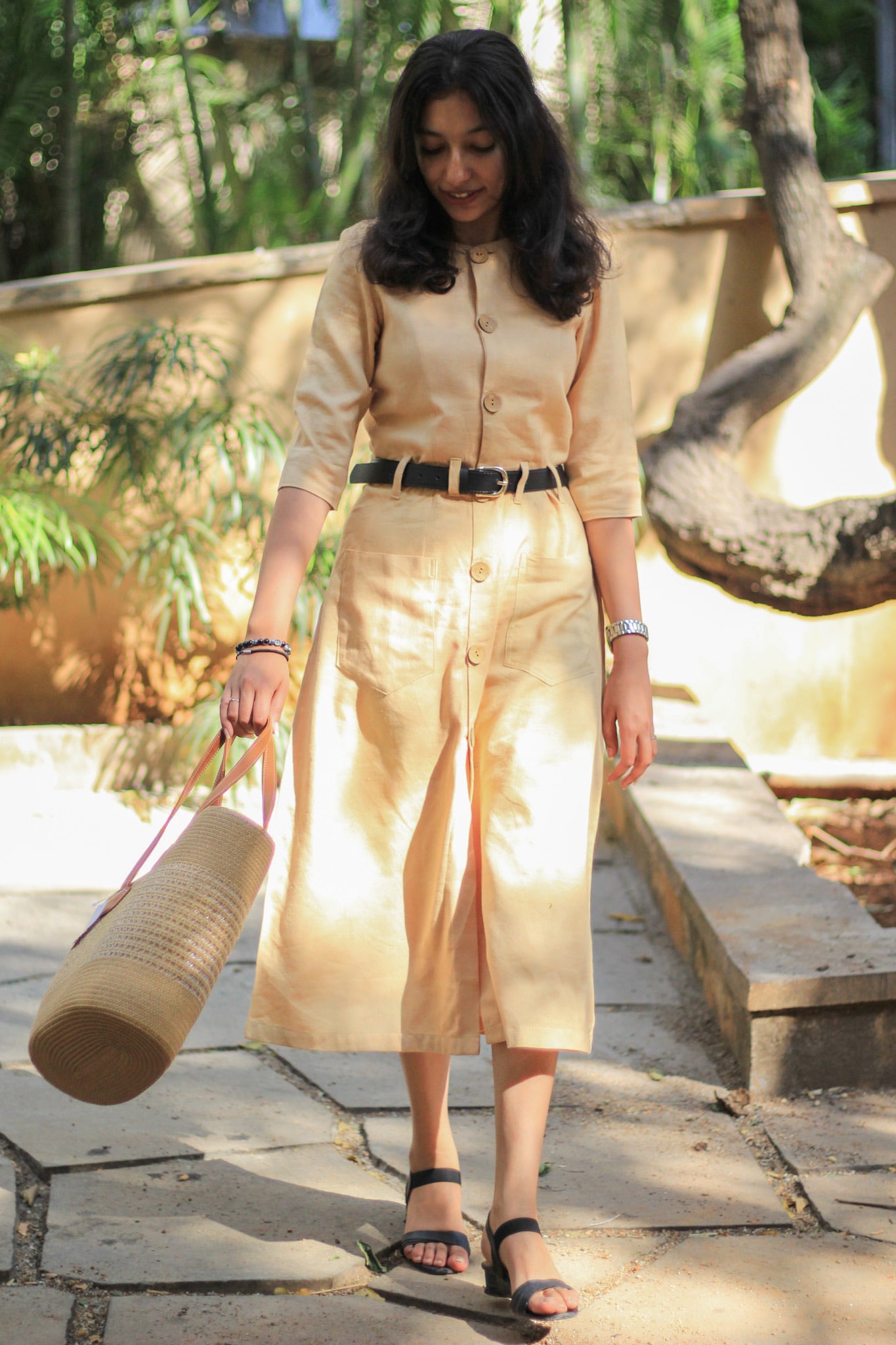 Model wearing Evara’s Golden Aura Button-Down Dress, crafted from a premium blend of banana fiber and cotton. This elegant midi dress in a warm golden hue features a structured silhouette, three-quarter sleeves, a classic button-down front, and functional patch pockets. Styled with a belt for a defined waist, it offers effortless sophistication for work or casual outings. Designed for consumers who appreciate natural fabrics and timeless fashion. Shop clothing at Evara.