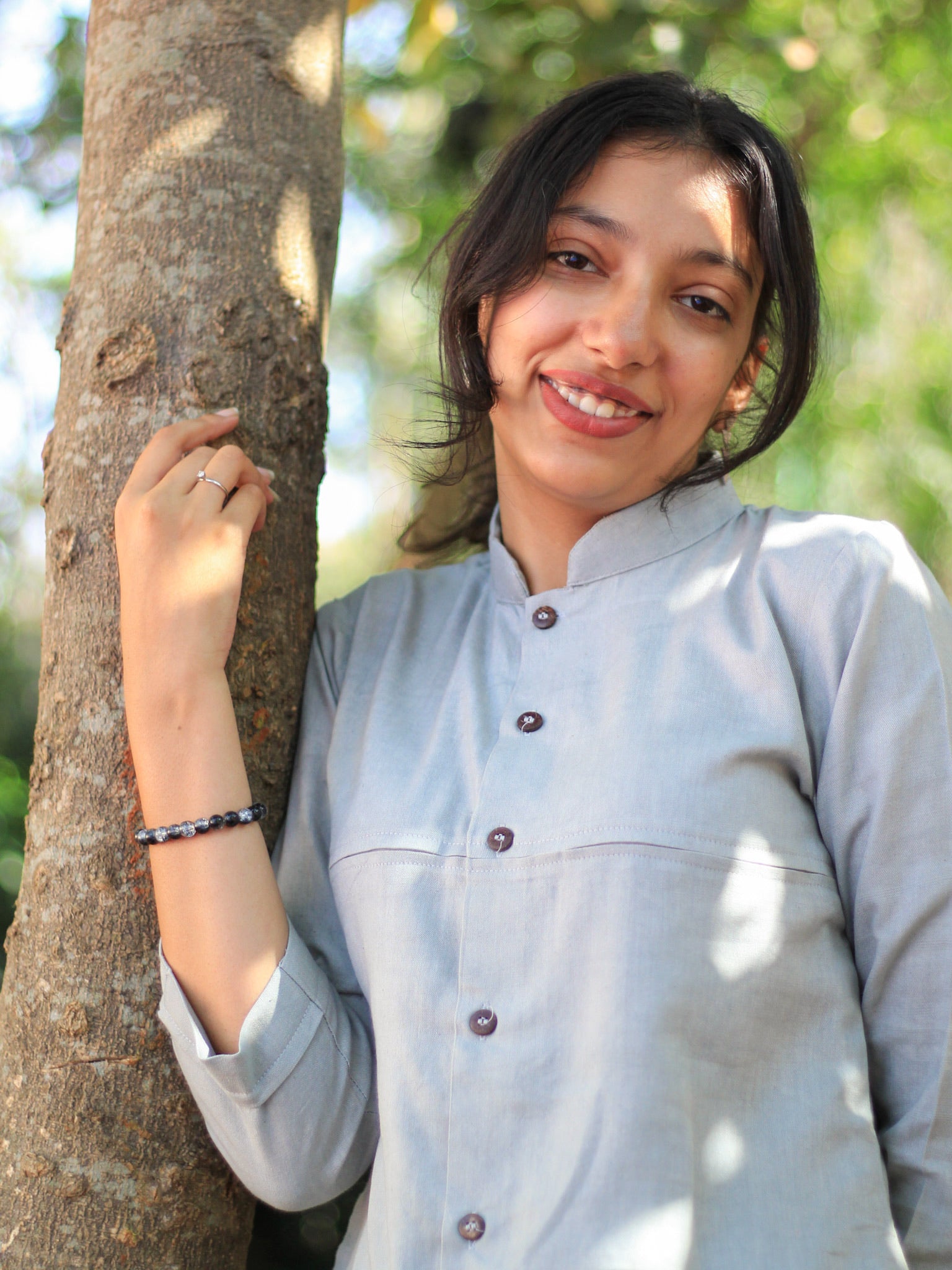 Model wearing Evara’s Smoky Pearl Button-Down Shirt, crafted from a premium blend of banana fiber and cotton. This elegant three-quarter sleeve shirt in a grey hue features a mandarin collar, a structured yet relaxed fit, and a stylish button-down front. Designed for effortless versatility, it pairs perfectly with both formal and casual looks. Designed for consumers who appreciate natural fabrics and timeless fashion. Shop clothing at Evara.