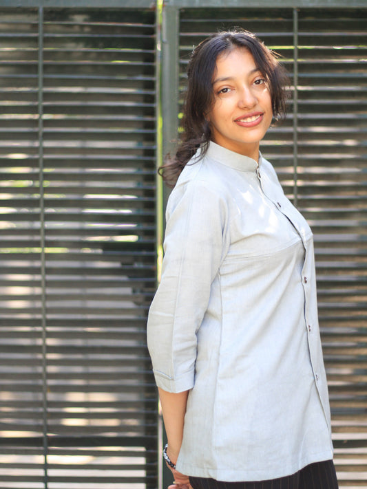 Model wearing Evara’s Smoky Pearl Button-Down Shirt, crafted from a premium blend of banana fiber and cotton. This elegant three-quarter sleeve shirt in a grey hue features a mandarin collar, a structured yet relaxed fit, and a stylish button-down front. Designed for effortless versatility, it pairs perfectly with both formal and casual looks. Designed for consumers who appreciate natural fabrics and timeless fashion. Shop clothing at Evara.