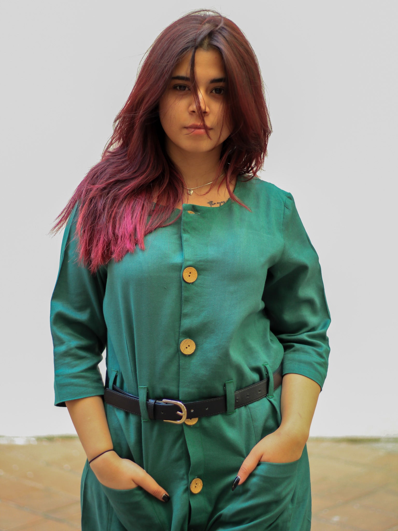 Model wearing Evara’s Botanic Luxe Button-Down Dress, crafted from a premium blend of banana fiber and cotton. This elegant midi dress in a green hue features a structured silhouette, three-quarter sleeves, a classic button-down front, and functional patch pockets. Styled with a belt for a defined waist, it offers effortless sophistication for work or casual outings. Designed for consumers who appreciate natural fabrics and timeless fashion. Shop clothing at Evara.