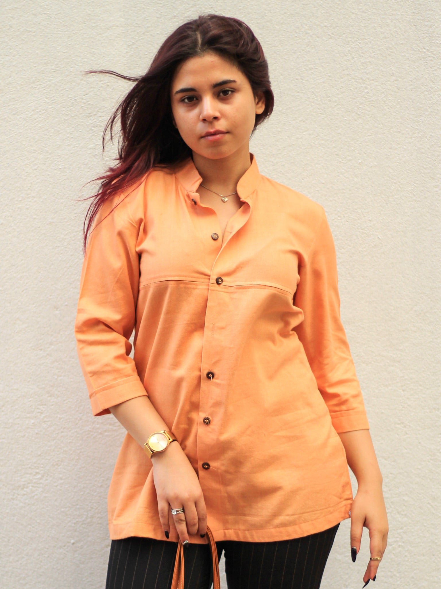 Model wearing Evara’s Coral Dusk Button-Down Shirt, crafted from a premium blend of banana fiber and cotton. This elegant three-quarter sleeve shirt in a warm coral hue features a mandarin collar, a structured yet relaxed fit, and a stylish button-down front. Designed for effortless versatility, it pairs perfectly with both formal and casual looks. Designed for consumers who appreciate natural fabrics and timeless fashion. Shop clothing at Evara.