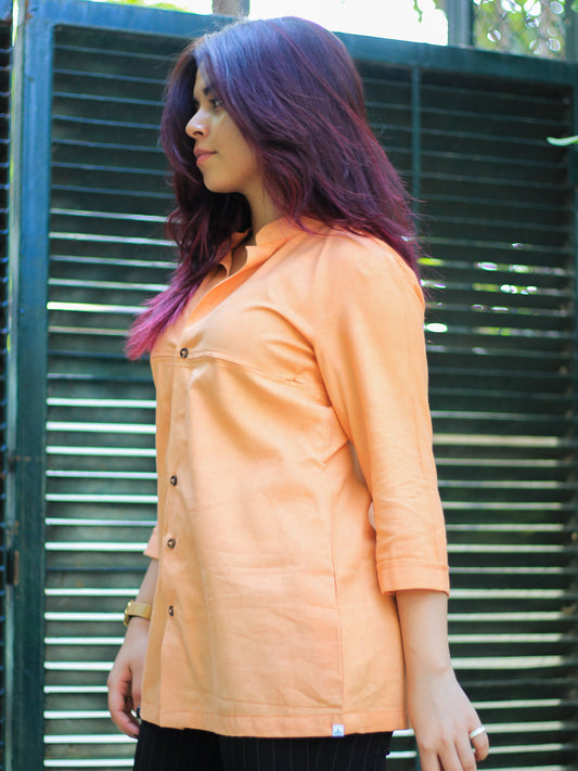 Model wearing Evara’s Coral Dusk Button-Down Shirt, crafted from a premium blend of banana fiber and cotton. This elegant three-quarter sleeve shirt in a warm coral hue features a mandarin collar, a structured yet relaxed fit, and a stylish button-down front. Designed for effortless versatility, it pairs perfectly with both formal and casual looks. Designed for consumers who appreciate natural fabrics and timeless fashion. Shop clothing at Evara.